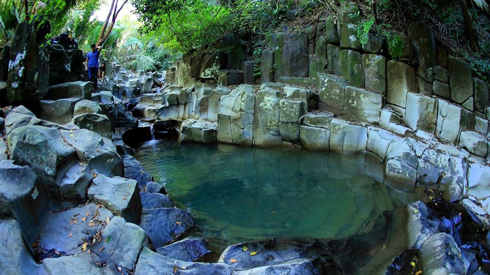 Poza de agua natural entre rocas volcánicas, cerca del predio